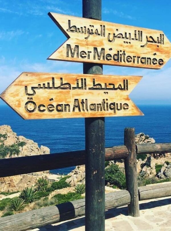 Wooden sign showing directions to the Mediterranean Sea and Atlantic Ocean in Tangier, a starting point for Morocco tours from Tangier.